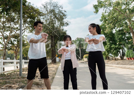 Family Enjoying Outdoor Exercise Together on a Sunny Day in a Park Setting with Trees and Clear Blue Sky Family Enjoying Outdoor Exercise Together on a Sunny Day in a Park Setting with Trees and Clear Blue Sky 129407102