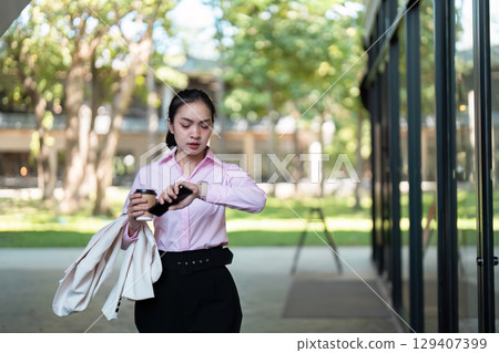 Business Professional Rushing to Work with Coffee and Smartphone in Urban Setting 129407399