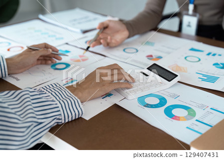 Business Team Analyzing Financial Data with Charts and Calculator in a Modern Office Setting 129407431