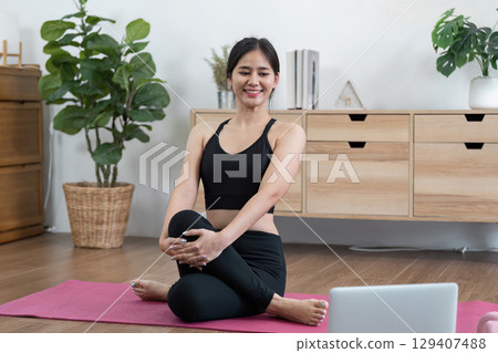 Young Woman Practicing Yoga at Home for Wellness and Relaxation in a Modern Living Room Setting Young Woman Practicing Yoga at Home for Wellness and Relaxation in a Modern Living Room Setting 129407488