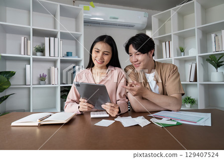 Young Couple Planning Finances Together with Tablet and Documents in Modern Home Office Setting 129407524