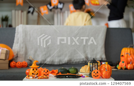 Halloween Fun. A mother and son decorating their living room with festive items. Halloween Fun. A mother and son decorating their living room with festive items. 129407569