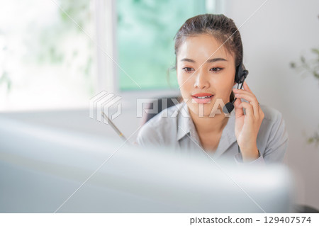Remote Work. Focused woman in headset providing customer service in office. Remote Work. Focused woman in headset providing customer service in office. 129407574