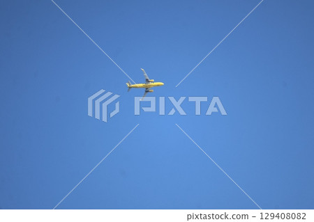 Skyscape with a yellow airplane flying in the blue sky 129408082