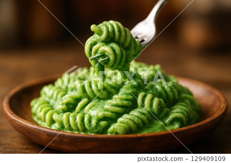 Delicious fusilli pasta with vibrant green spinach cream sauce on wooden plate Delicious fusilli pasta with vibrant green spinach cream sauce on wooden plate 129409109
