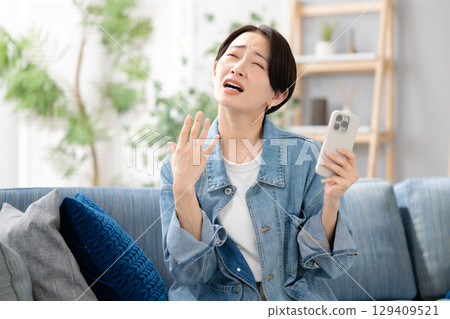 A woman looking at her smartphone in the living room 129409521