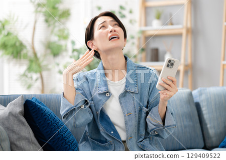 A woman looking at her smartphone in the living room 129409522