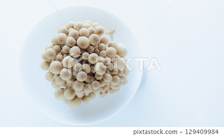 生的姬菇放在白色的盤子裡,簡單的俯視圖,白色背景 生的姬菇放在白色的盤子裡,簡單的俯視圖,白色背景 129409984