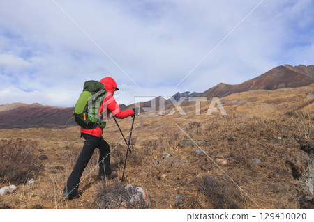Backpacking woman hiking on winter high altitude mountain top 129410020