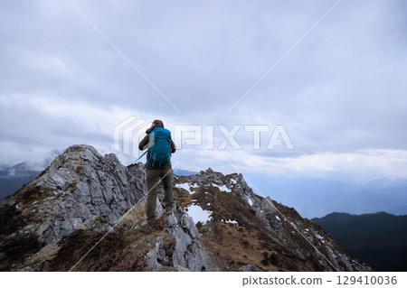 Backpacking woman hiker hiking at mountain top in tibet 129410036