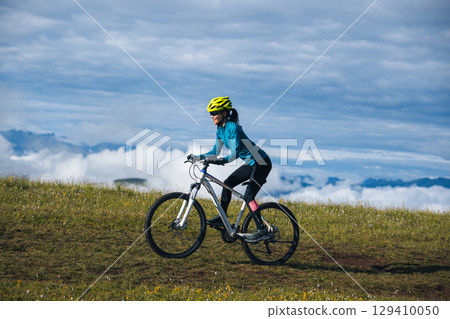 Asian woman riding mountain bike on beautiful mountain top 129410050