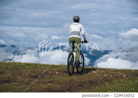 Asian woman riding a mountain bike down hill on beautiful mountain top Asian woman riding a mountain bike down hill on beautiful mountain top 129410052