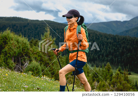 Hiking woman climbing up to  high altitude forest mountain top 129410056