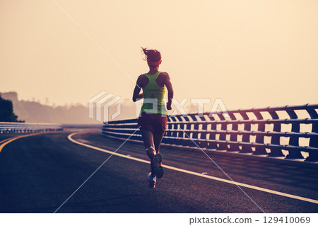 Fitness asian woman runner running on seaside bridge Fitness asian woman runner running on seaside bridge 129410069
