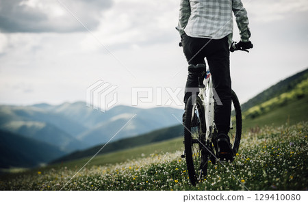 Riding mountain bike in the beautiful flowering grassland mountains Riding mountain bike in the beautiful flowering grassland mountains 129410080