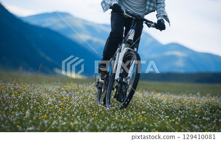 Riding mountain bike in the beautiful flowering grassland mountains Riding mountain bike in the beautiful flowering grassland mountains 129410081