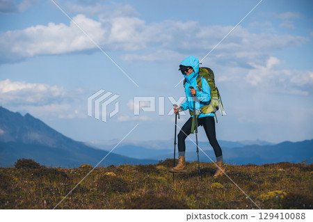 Backpacking woman hiking on sunset high altitude mountain top 129410088