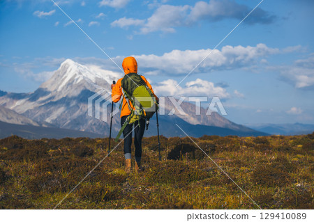 Backpacking woman hiking on sunset high altitude mountain top 129410089