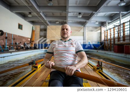 Focused forced rowing athletes train intensely on rowing simulator during synchronized team workout 129410601