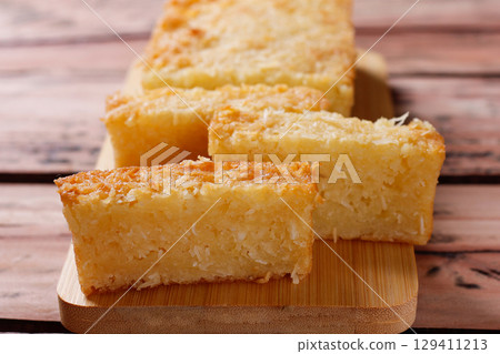 Traditional homemade cassava cake whit coconut on a rustic wooden table Traditional homemade cassava cake whit coconut on a rustic wooden table 129411213