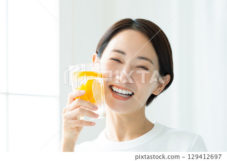 一位年輕女子帶著燦爛的笑容,手裡拿著一杯檸檬水,面朝上 一位年輕女子帶著燦爛的笑容,手裡拿著一杯檸檬水,面朝上 129412697