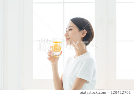 一位透明的年輕女子拿著一杯檸檬水，上身 129412701