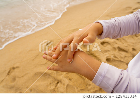 Child smears sunscreen on his hands Child smears sunscreen on his hands 129413314