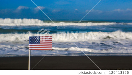 American national flag on a sandy beach with the sea in the background. Travel destination and Independence day concept  129413536
