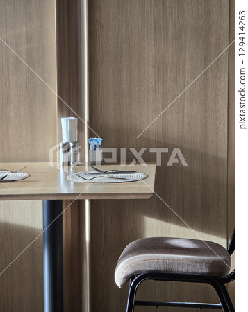 wooden table with decorative placemat, glass, and chair in cozy setting. warm tones create welcoming atmosphere, perfect for dining or relaxation 129414263