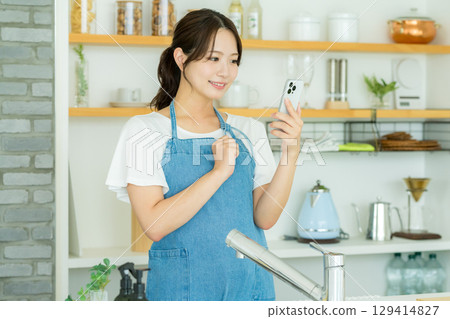 站立在廚房裡的一個微笑的少婦 129414827