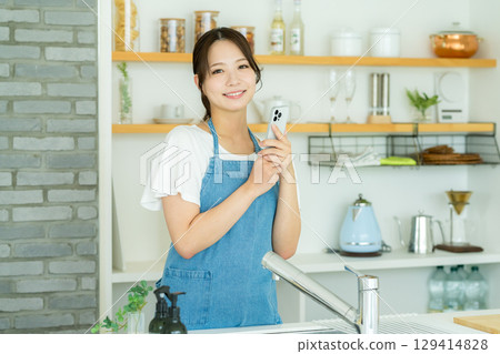 站立在廚房裡的一個微笑的少婦 站立在廚房裡的一個微笑的少婦 129414828