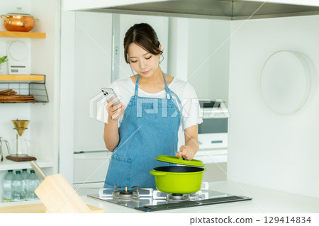 A smiling young woman standing in the kitchen 129414834