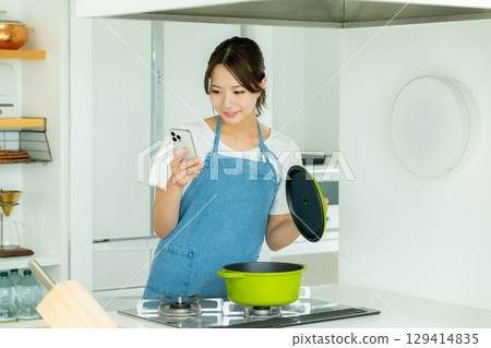 站立在廚房裡的一個微笑的少婦 129414835