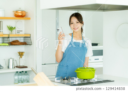 A smiling young woman standing in the kitchen A smiling young woman standing in the kitchen 129414838