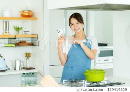 A smiling young woman standing in the kitchen 129414839