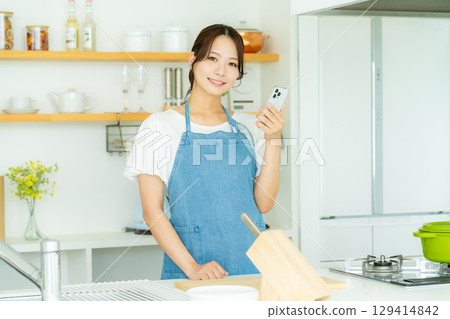 站立在廚房裡的一個微笑的少婦 129414842