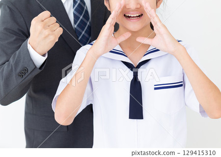 一名身穿夏季校服的中學生在歡呼,她的父親則穿著西裝 一名身穿夏季校服的中學生在歡呼,她的父親則穿著西裝 129415310