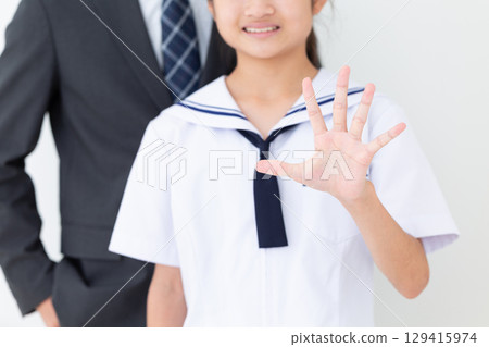 一名身穿夏季校服的中學生和她身穿西裝、舉起五根手指的父親 129415974