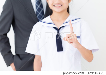 一名身穿夏季校服的中學生用食指指著，她的父親穿著西裝 129416335