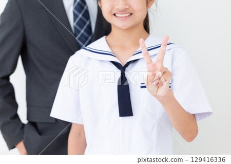 一名身穿夏季校服的中學生和她身穿西裝的父親舉起兩根手指 一名身穿夏季校服的中學生和她身穿西裝的父親舉起兩根手指 129416336