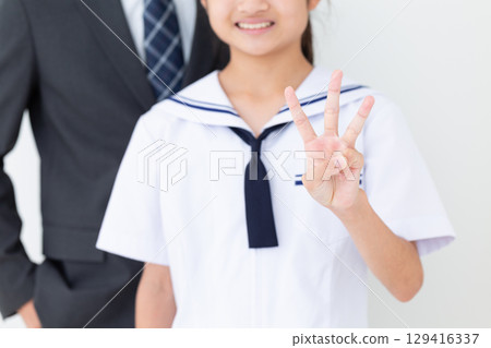 A middle school girl in a summer school uniform and her father in a suit holding up three fingers 129416337