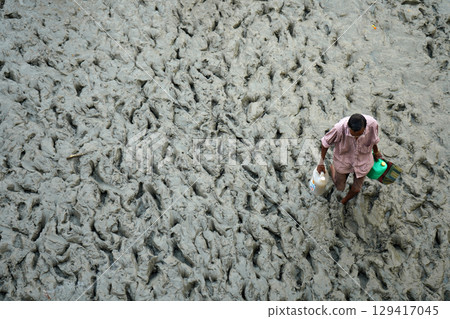 14th October 2023, Babughat, Kolkata, West Bengal, India. Man Carrying Containers Through Muddy 14th October 2023, Babughat, Kolkata, West Bengal, India. Man Carrying Containers Through Muddy 129417045
