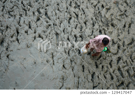 14th October 2023, Babughat, Kolkata, West Bengal, India. Man Walking Barefoot on Muddy Terrain 129417047