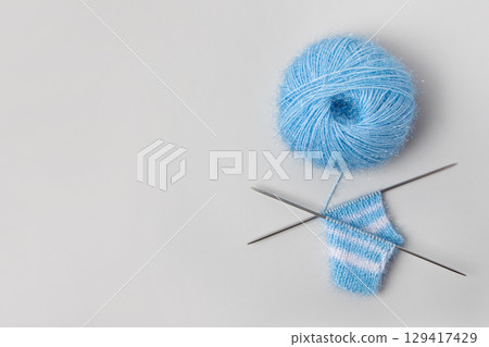 Blue knitted wool on gray background with knitting needles for knitting warm clothes and hobbies needlework 129417429
