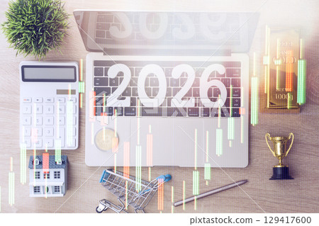 Stock market overlay on workspace with 2026 on laptop, surrounded by gold bar, bitcoin, house, calculator, and trophy symbolizing future investments. 129417600