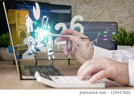 Businessman uses digital tablet and calculator with 2026 financial icons overlayed, including economy, shopping, equity, and real estate. 129417602