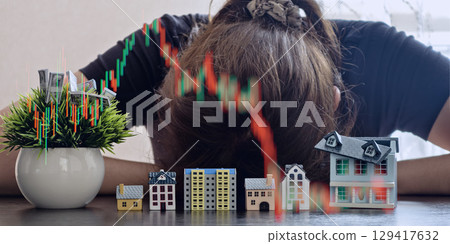 dejected investor with his head down, faced with financial losses represented by falling real estate investment charts. dejected investor with his head down, faced with financial losses represented by falling real estate investment charts. 129417632
