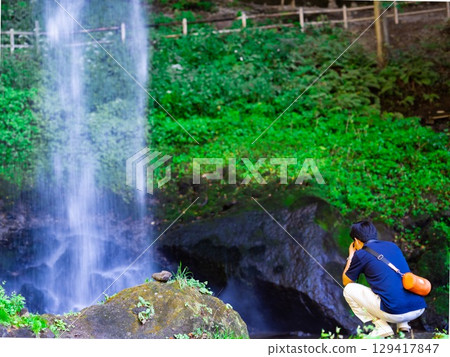 A man taking a photo of the waterfall 129417847
