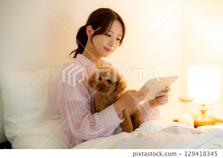 A woman watching a tablet in bed A woman watching a tablet in bed 129418345