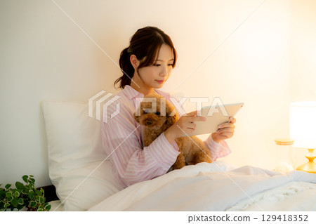 A woman watching a tablet in bed 129418352